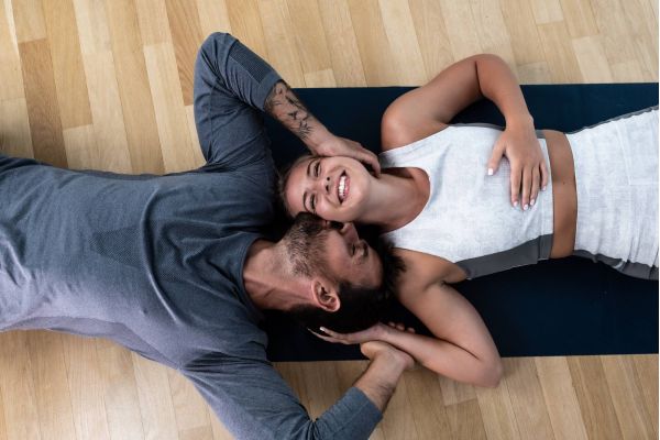 Attain on 5th apartment homes with A smiling woman lies on a yoga mat as a man rests beside her, holding her face and hand affectionately.