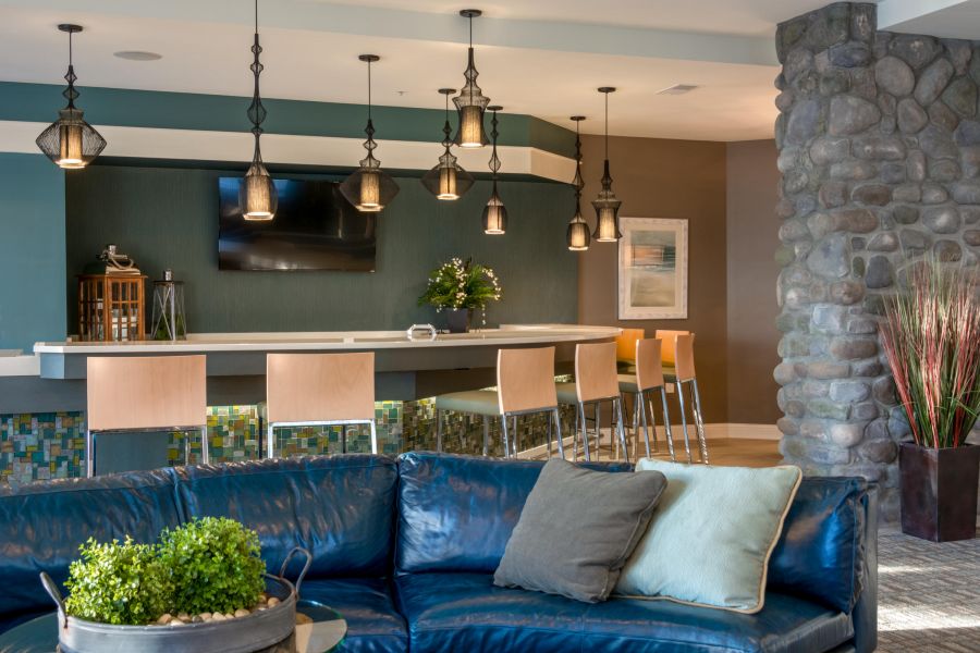Modern lounge with a blue leather sofa, bar seating, pendant lights, and a stone accent wall.