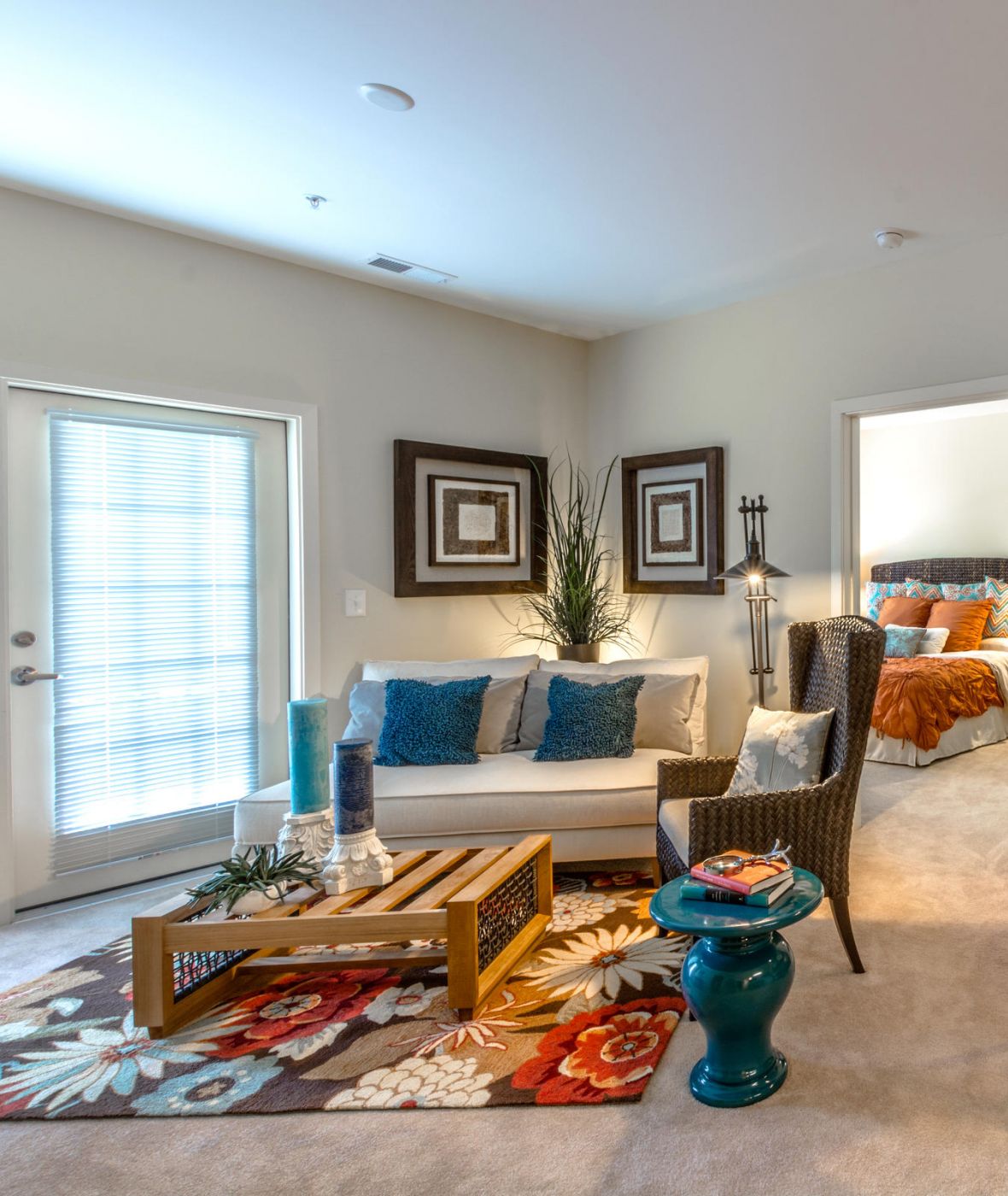 A colorful living and dining area with modern decor, a white sofa, and a round table beside a teal accent wall.