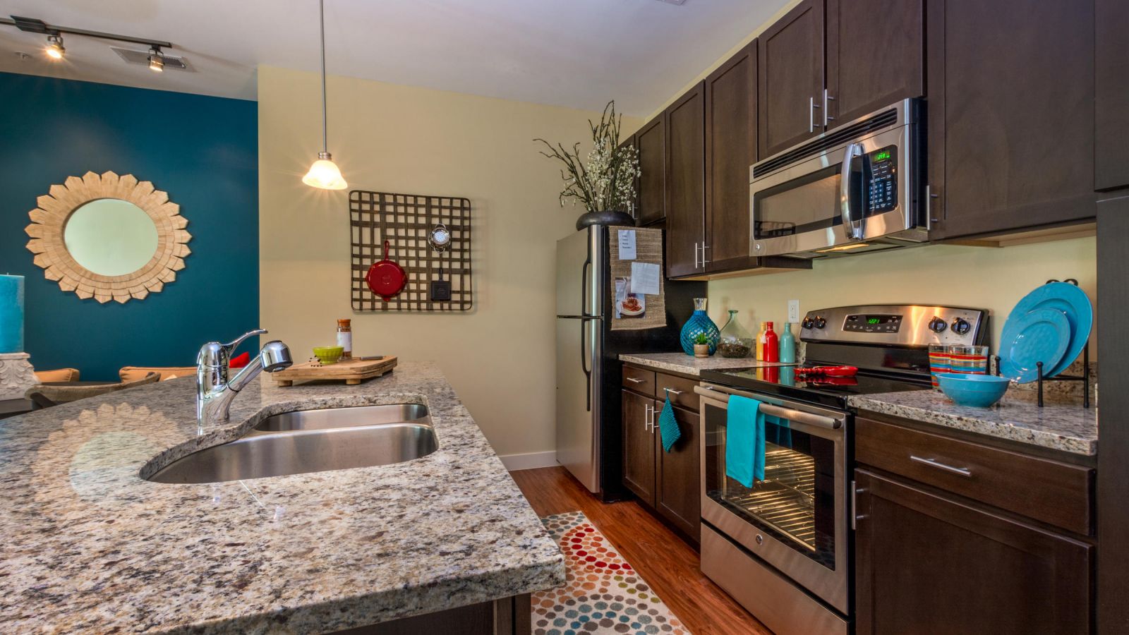 Modern kitchen and living area with white cabinets, stainless steel appliances, and a large island. Cozy seating area with a sofa and rug in the background. Bright and inviting atmosphere.