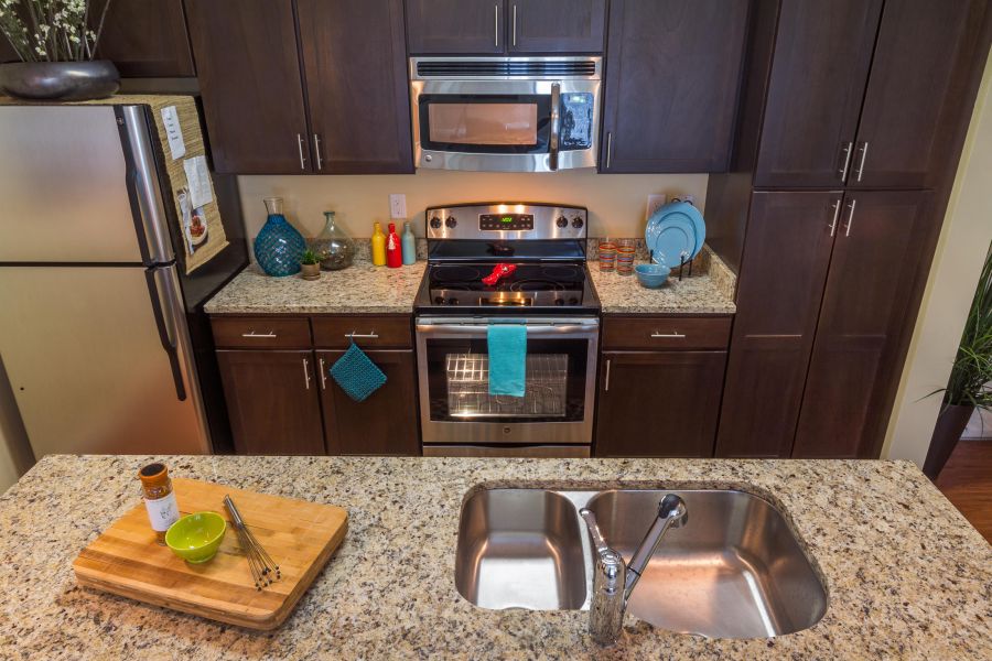 Modern kitchen with dark cabinets, stainless steel appliances, and a granite countertop with a sink.